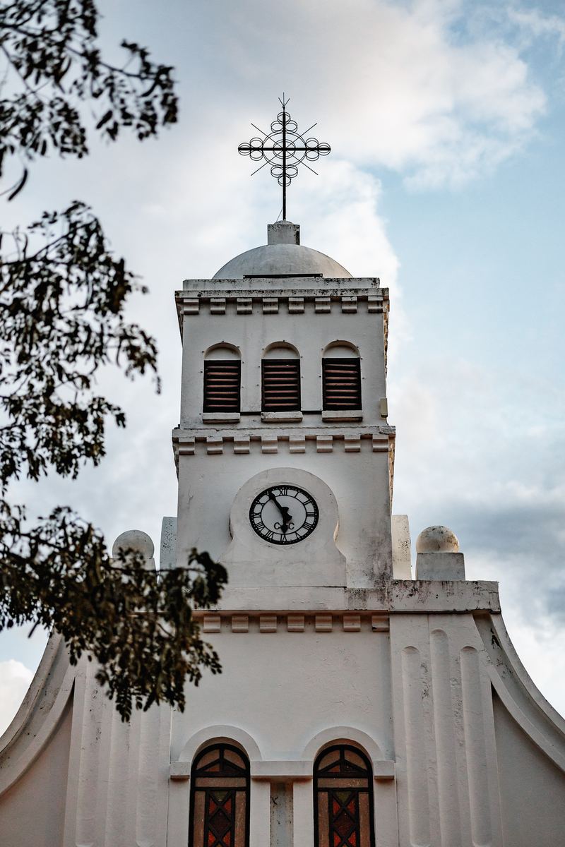 La fachada blanca de la iglesia de Cauca Viejo con su reloj y su cruz