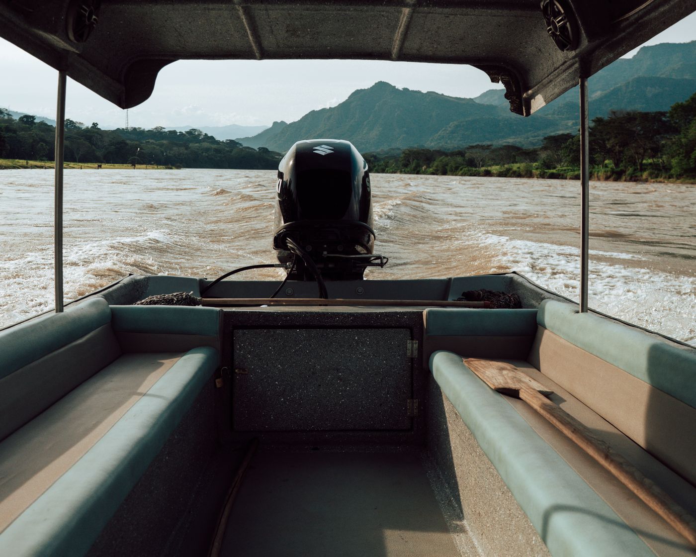 Desde adentro de la lancha en marcha: el motor, la estela sobre el río Cauca y las montañas al fondo